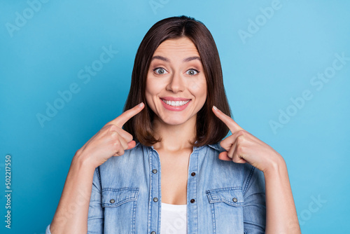 Photo of pretty adorable lady dressed denim shirt pointing fingers white teeth isolated blue color background