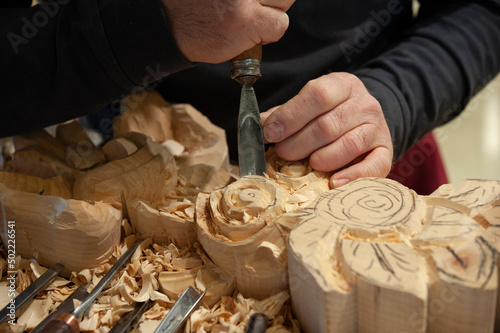 Master woodcarver at work. Wood shavings, gouges and chisels on the workbench.