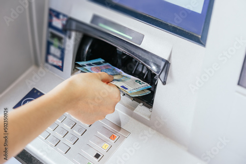 Close up of a woman's hand withdrawing cash, euro bills from the ATM bank machine. Finance customer and banking service concept