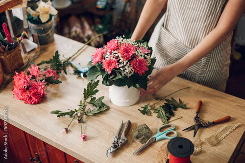 Florist woman creating flower arrangement in a round box