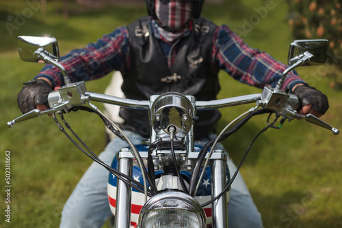 Selective focus shot of a driver riding a USA themed harley Davidson with a helmet on