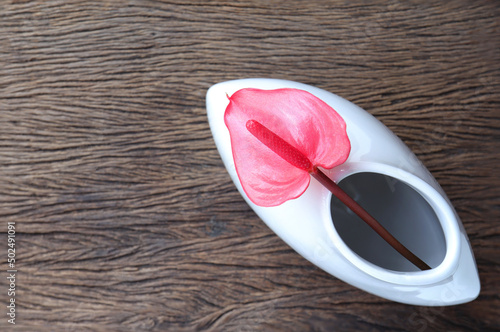 Red Anthurium flower, anthurium or flamingo flowers in vase on the wooden table. Top view, Minimal modern interior concept with empty space for text.