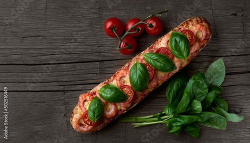 Homemade baguette sandwich or pizza with shrimp, cherry tomatoes and fresh basil leaves on top. Top view photo on a wooden background in a rustic style with place for your text.