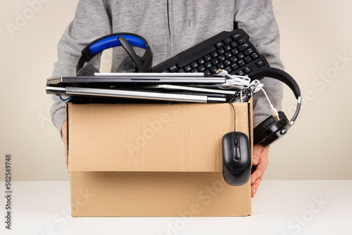 Woman hands holding cardboard box full old used computers, phones, tablets, gadget devices for recycling. Planned obsolescence, e-waste, donation, electronic waste for reuse and recycle concept