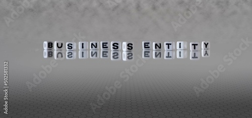 business entity word or concept represented by black and white letter cubes on a grey horizon background stretching to infinity