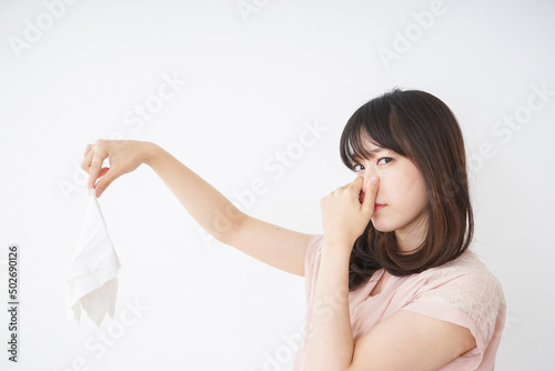 臭い洗濯物の匂いを嗅ぐ若い女性