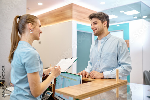 Man talking to professional receptionist in clinic