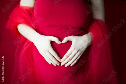 9 miesięcy ciąży, kobieta i mężczyzna trzymają ręce w kształcie serca na brzuchu ciążowym