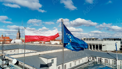 Waving polisg flag and european union flag on building