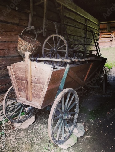 Stary, zabytkowy drewniany wóz wiejski z dużymi kołami obok drewnianej stodoły