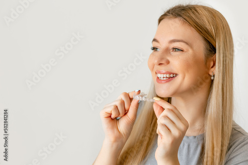 Orthodontics. Closeup Of Beautiful Happy Smiling Woman With White Smile, Straight Teeth Holding Whitening Tray, Invisible Braces, Teeth Trainer. Dental Treatment. Copy space