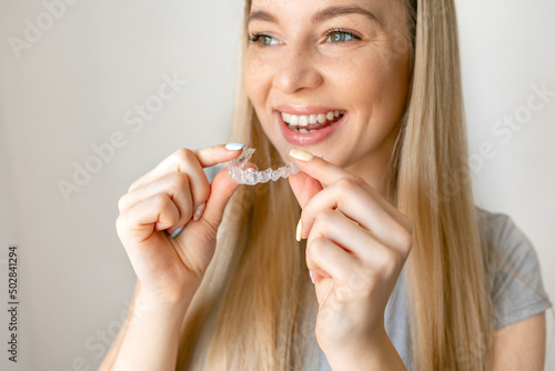 Dental care. Smiling woman with healthy teeth using removable clear braces aligner, orthodontic silicone trainer.