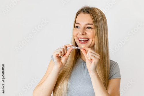 Dental care. Smiling woman with healthy teeth using removable clear braces aligner, orthodontic silicone trainer. Copy space