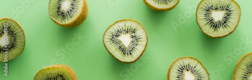 flat lay of juicy fresh kiwi fruit on green, banner.