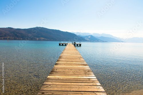 Panoramic view of Lake Attersee with wooden pier and mountain range in the background. Salzkammergut Upper Austria