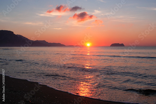 Bright colorful dramatic sunrise landscape. Unfocused sun rises over the colourful sea. Sunrise view on the Kalamaki beach Zakynthos island Greece