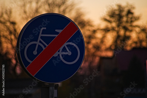 Znak drogowy ; " koniec drogi dla rowerów " , na tle ciemnego nieba podczas zachodu słońca .