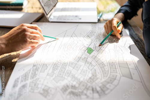 Human Hand Holding Pencil Over Cadastre Map