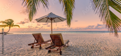 Beautiful panoramic nature. Tropical beach sunset as summer island landscape with chairs umbrella palm leaves calm sea shore, coast. Luxury travel panoramic destination banner for vacation or holiday