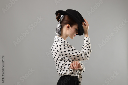 Woman with black hat and stylish bandana on light grey background