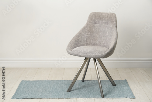 Stylish beige chair near white wall indoors. Space for text