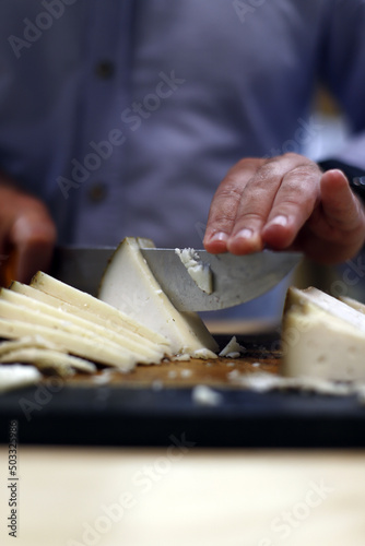 manos cortando queso con un cuchillo en la tabla de corte
