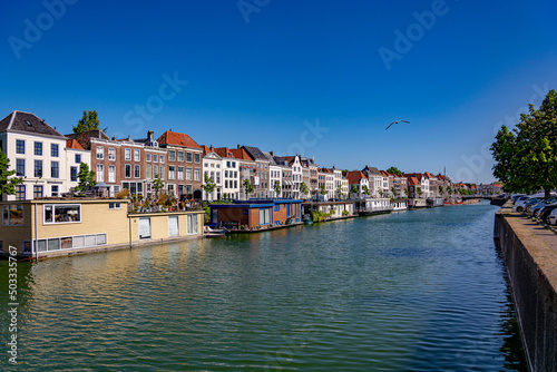 Sunny summer day by the water canal in Middelburg, facing the row of a building facades