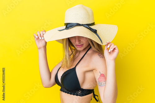 Young Romanian woman isolated on yellow background in swimsuit in summer holidays