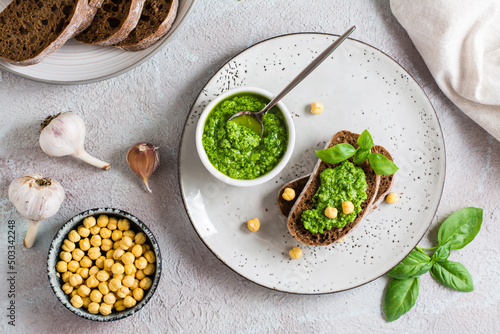 Fresh sandwich with pesto and chickpeas on rye bread on a plate on the table. Top view