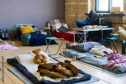 Part of spacious room with sleeping places on wooden floor for refugees or temporarily homeless people because of war or cataclysm