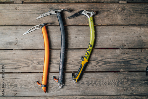 Detail photo of different ice climbing tools. Ice climbing gear, ice axe on a wooden background. Alpinist or mountaineer climbing equipment.