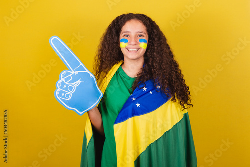 Brazilian, Caucasian, soccer fan girl with foam hand cheering for world cup, soccer fan, brazilian fan clothes.