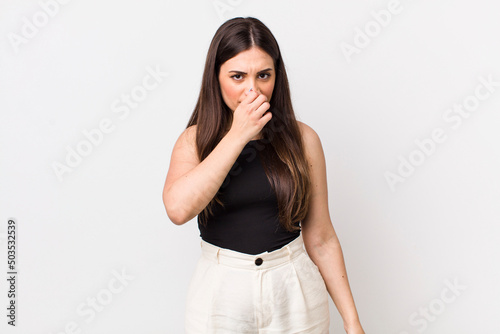 young pretty woman feeling disgusted, holding nose to avoid smelling a foul and unpleasant stench