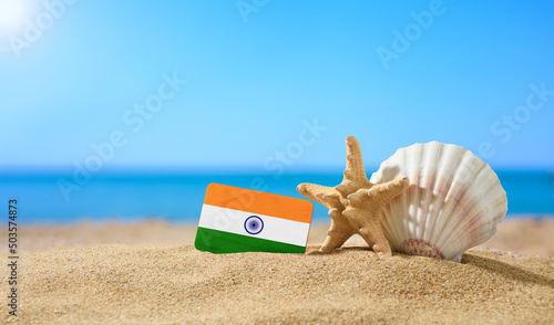 Tropical beach with seashells and India flag. The concept of a paradise vacation on the beaches of India.