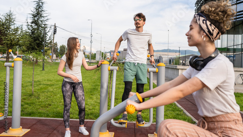 Group of friends man and women male and young adult people training at outdoor open gym in park in front of modern building real people sport and recreation exercise healthy lifestyle concept
