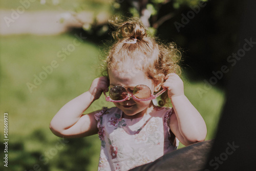 Mała dziewczynka próbuje założyć okulary przeciwsłoneczne