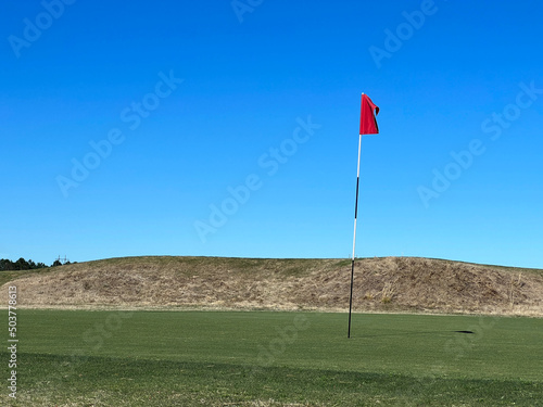 golf course with red flag on the green