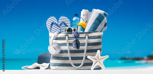 Beach bag with accessories and tropical beach
