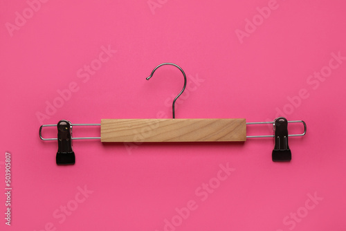 Empty wooden hanger with clips on pink background, top view