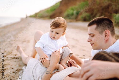 Father, mother and child resting on the beach. Young family are having fun on summer vacation. Travel, nature, active lifestyle, resort concept.