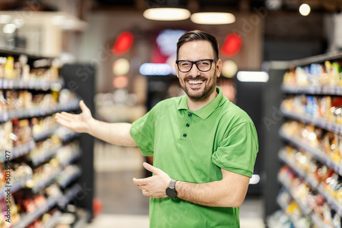 Friendly employee welcoming customers in supermarket.