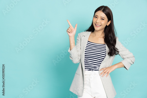 Young beautiful Asian business woman pointing to empty copy space isolated on green background