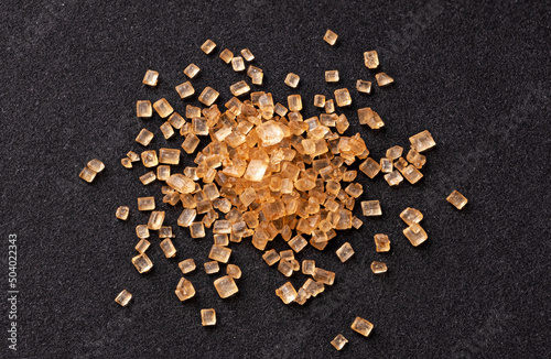 Pile of cane sugar on black background, top view