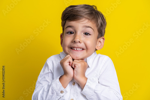 Front view of small caucasian boy four years old standing in front of yellow background studio shot child making poses looking to the camera surprised or impatient copy space