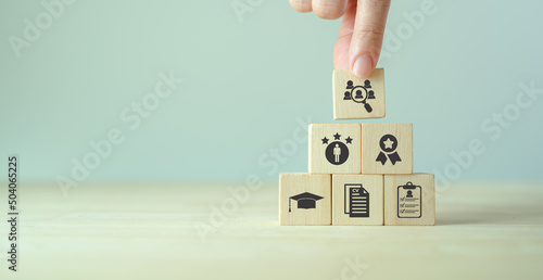 HRM and recriutement concept. Job search, headhunting and recruitment process. Holding wooden cubes with icons of education, qualification, cv, resume, skills and experience on smart grey background.