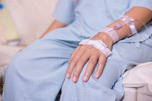 Hands patient woman receiving saline solution during sitting on sick bed at hospital