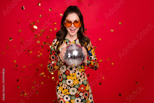 Portrait of attractive cheerful girly girl holding silver disco ball having fun isolated over bright red color background