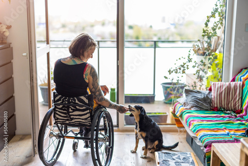 Young woman in wheelchair with her dog at home