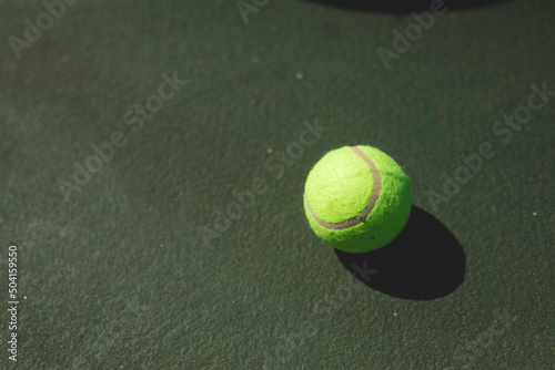 Directly above view of green tennis ball with shadow on gray court during sunny day
