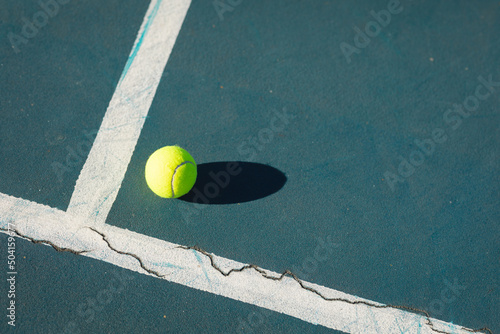 High angle view of green ball with shadow by line on blue tennis court during sunny day